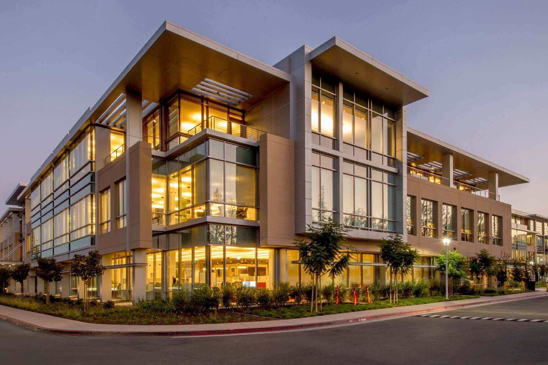 Modern commercial office building with glass facade at sunset